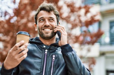 Sakallı yakışıklı, dışarıda mutlu bir şekilde gülümseyen telefonda konuşan adam.