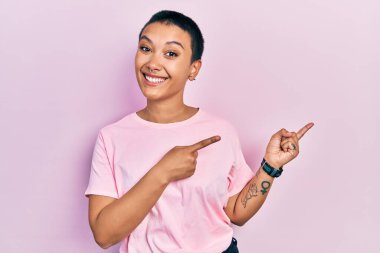 Kısa saçlı, pembe tişörtlü güzel İspanyol kadın endişeli ve gergin bir tarafı işaret ediyor. Endişeli ve şaşırmış bir ifade. 