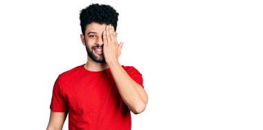 Sakallı, sıradan kırmızı tişörtlü genç bir Arap. Bir gözünü eliyle kapatıyor. Yüzünde kendine güvenen bir gülümseme ve sürpriz bir duygu var.. 