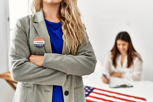 American voter woman wearing i voted badge standing with arms crossed gesture at electoral college.