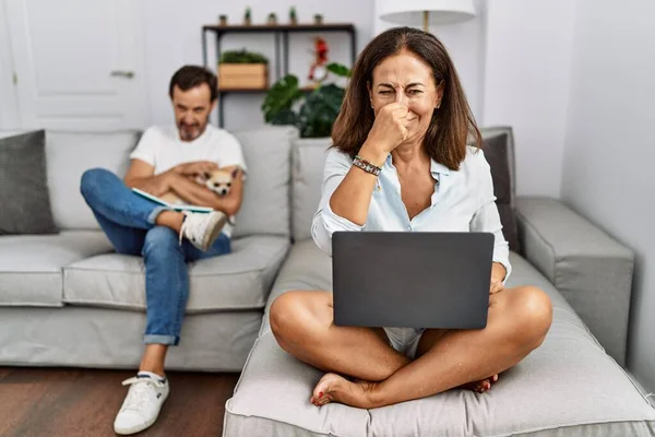 Hispanic Middle Age Couple Home Woman Using Laptop Smelling Something — Stockfoto