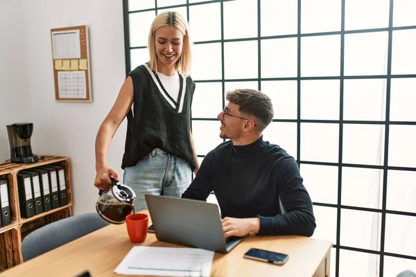 Two business workers smiling happy working and drinking coffee at the office.