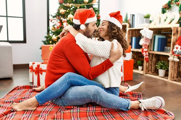 Latynoska Para Średnim Wieku Ubrana Świąteczny Kapelusz Siedząca Podłodze Przytulająca — Zdjęcie stockowe