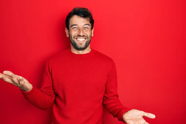 優しい歓迎 正と自信を持って挨拶として腕を開いて陽気に笑顔カジュアルな赤いセーターを身に着けている髭のハンサムな男 — ストック写真