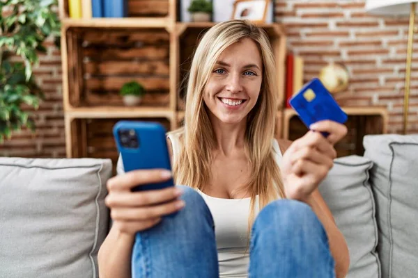Junge Blonde Frau Sitzt Mit Smartphone Und Kreditkarte Hause Auf — Stockfoto