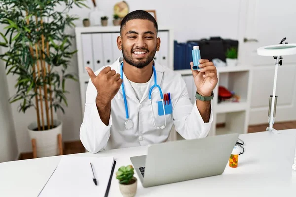 Young Indian Doctor Holding Medical Asthma Inhaler Clinic Pointing Thumb — Fotografia de Stock