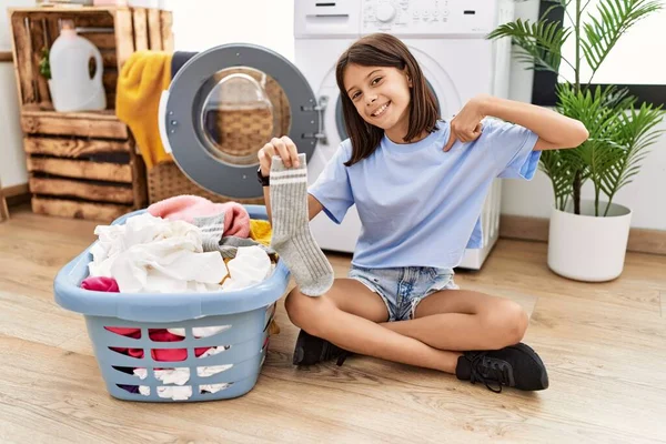 Young Hispanic Girl Doing Laundry Holding Socks Looking Confident Smile — 스톡 사진