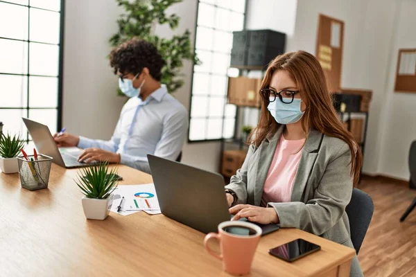 Two business workers wearing medical mask working at the office.
