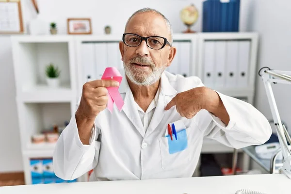 Mature Doctor Man Holding Pink Cancer Ribbon Clinic Pointing Finger — Foto Stock