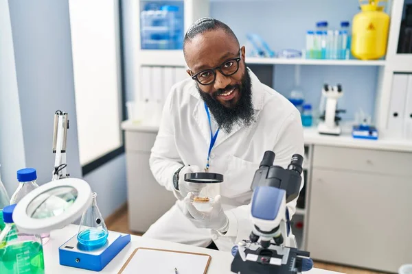 若いアフリカ系アメリカ人の男研究室でルーペを使って科学者の制服を着て — ストック写真