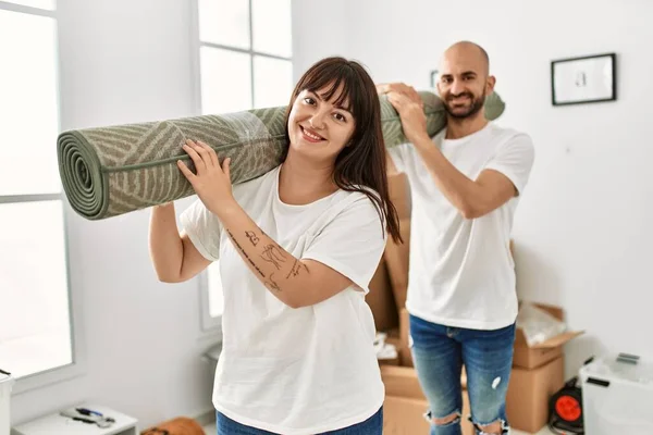 Jovem Casal Hispânico Sorrindo Feliz Segurando Tapete Nova Casa — Fotografia de Stock