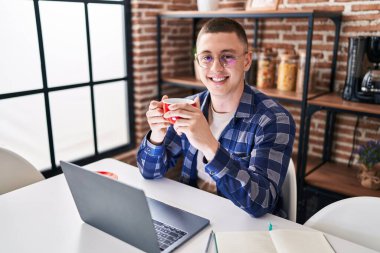 Young hispanic man drinking coffee sitting on table studying at home