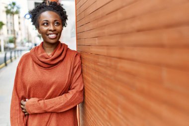 Genç Afrikalı Amerikalı kız gülümseyerek şehirde mutlu mesut duruyor..