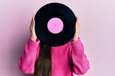 Pembe arka planda retro vinil disk tutan kadın.
