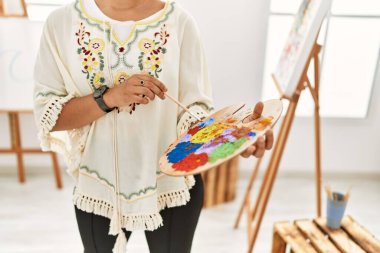 Genç İspanyol kadın sanat stüdyosunda renkleri karıştırıyor.