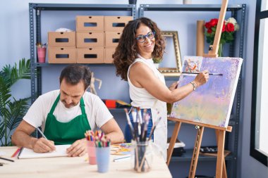 Man and woman artists smiling confident drawing at art studio