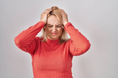 Blonde woman standing over isolated background suffering from headache desperate and stressed because pain and migraine. hands on head. 