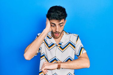 Gündelik giysiler giyen genç İspanyol adam saate bakıyor. Endişeli, geç kalmaktan korkuyor. 