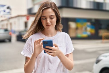 Sokakta akıllı telefon kullanan kendine güvenen genç bir kadın.