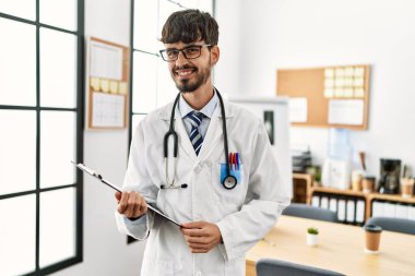 Klinikte çalışırken gülümseyen genç İspanyol doktor.