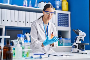 Laboratuvarda eldiven giyen genç Afrikalı Amerikalı kadın bilim adamı.