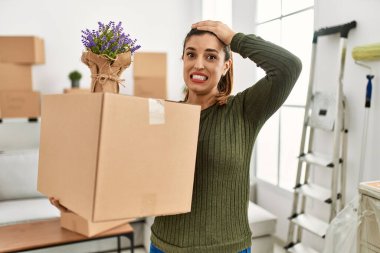 Hareket halindeyken elinde karton kutu tutan genç İspanyol kadın. Stresli ve hayal kırıklığına uğramış, şaşırmış ve kızgın yüzlü. 