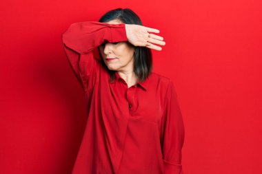 Middle age hispanic woman wearing casual clothes covering eyes with arm, looking serious and sad. sightless, hiding and rejection concept 