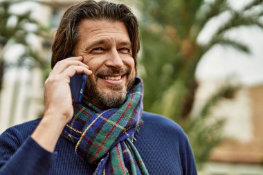 Orta yaşlı yakışıklı adam parkta dışarıda telefonla konuşuyor.