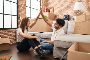 Erkek ve kadın çift gülümsüyor. Kendine güvenen bir beşlik. Yeni evlerinde eller havada.