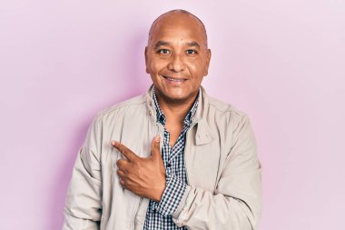 Middle age latin man wearing casual clothes smiling cheerful pointing with hand and finger up to the side 