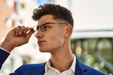 Genç adam sokakta takım elbise ve gözlük takarak rahatladı.