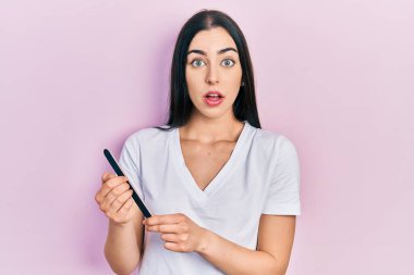 Mavi gözlü güzel bir kadın dosya çivisi kullanıyor. Şaşırmış ve şaşırmış bir ifade, korku ve heyecanlı bir yüz ifadesi var.. 