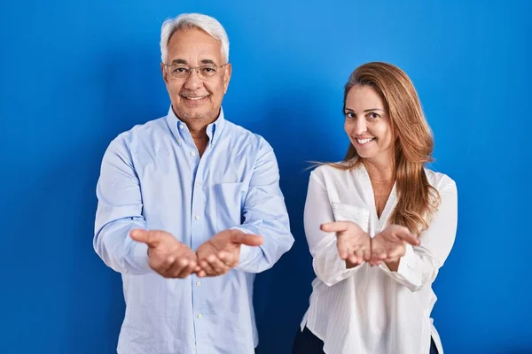 Middle Age Hispanic Couple Standing Blue Background Smiling Hands Palms — kuvapankkivalokuva