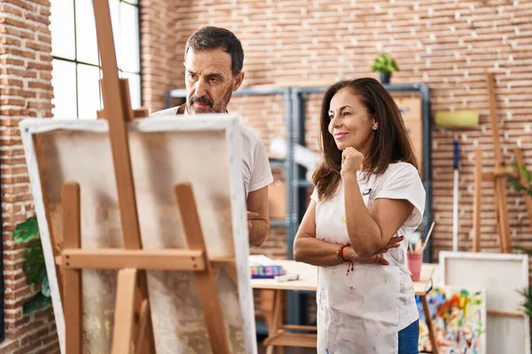 Sanat stüdyosunda çizim yapan orta yaşlı erkek ve kadın sanatçılar.