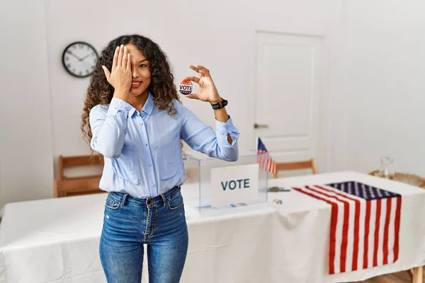 一つの目を手で覆い自信に満ちた笑顔と驚きの感情で投票することによって政治運動に立っている美しいヒスパニック系の女性 — ストック写真