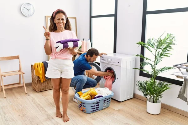 Middle Age Couple Holding Clean Laundry Smiling Happy Pointing Hand — Stok fotoğraf