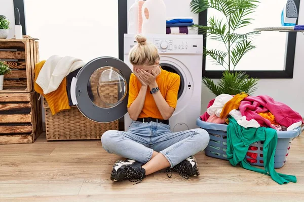 Young Blonde Woman Doing Laundry Sitting Washing Machine Sad Expression — Stockfoto