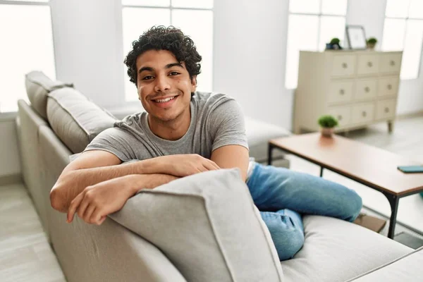 Νεαρός Ισπανόφωνος Χαμογελαστός Χαρούμενος Κάθεται Στον Καναπέ Στο Σπίτι — Φωτογραφία Αρχείου