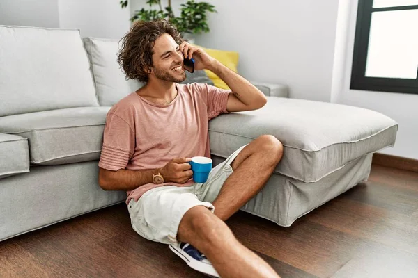 Ung Latinamerikan Man Dricka Kaffe Och Prata Smartphone Sitter Golvet — Stockfoto