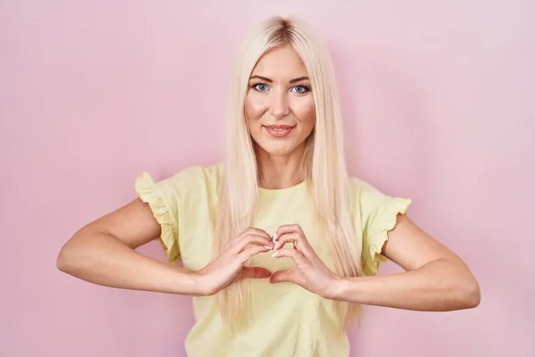 Caucasian Woman Standing Pink Background Smiling Love Doing Heart Symbol — Fotografia de Stock
