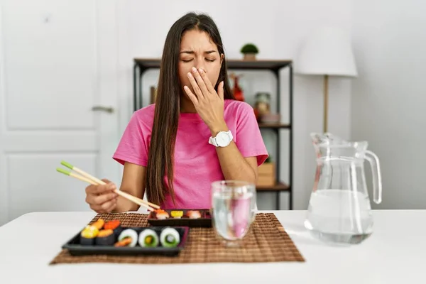 箸を使って寿司を食べる若いブルネットの女性は手で疲れたカバー口をあくび退屈 落ち着きもなく眠気もなく — ストック写真