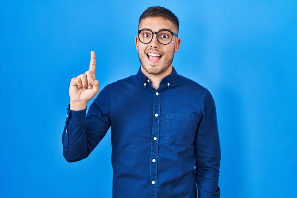 Een Jonge Spaanse Man Met Een Bril Een Blauwe Achtergrond — Stockfoto