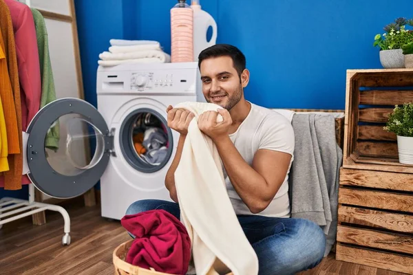 Young Hispanic Man Smiling Confident Smelling Clothes Laundry Room — Stock Fotó