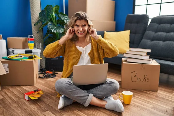 Young Woman Sitting Floor New Home Using Laptop Covering Ears — Stockfoto