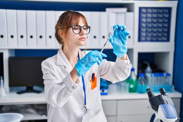 Young woman scientist holding vaccine at laboratory
