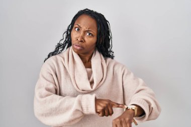 African woman standing over white background in hurry pointing to watch time, impatience, upset and angry for deadline delay 