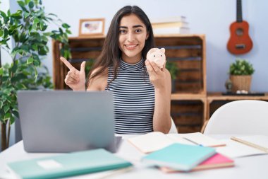 Bilgisayarla çalışan genç bir kız mutlu bir şekilde gülümseyerek elini ve parmağını kenarda gezdiriyor. 