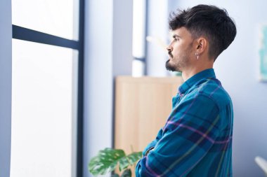 Young hispanic man standing with arms crossed gesture at home