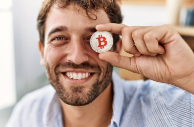 Genç İspanyol işadamı gülümsüyor. Ofiste Bitcoin 'i gözünün önünde tutarken mutlu..