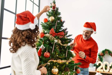 Orta yaşlı İspanyol çift gülümsüyor. Mutlu noel ağacı süslüyor evde..